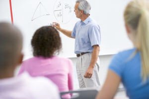 a teacher talks to school children in a high school class StrpPhABo e1522685184440